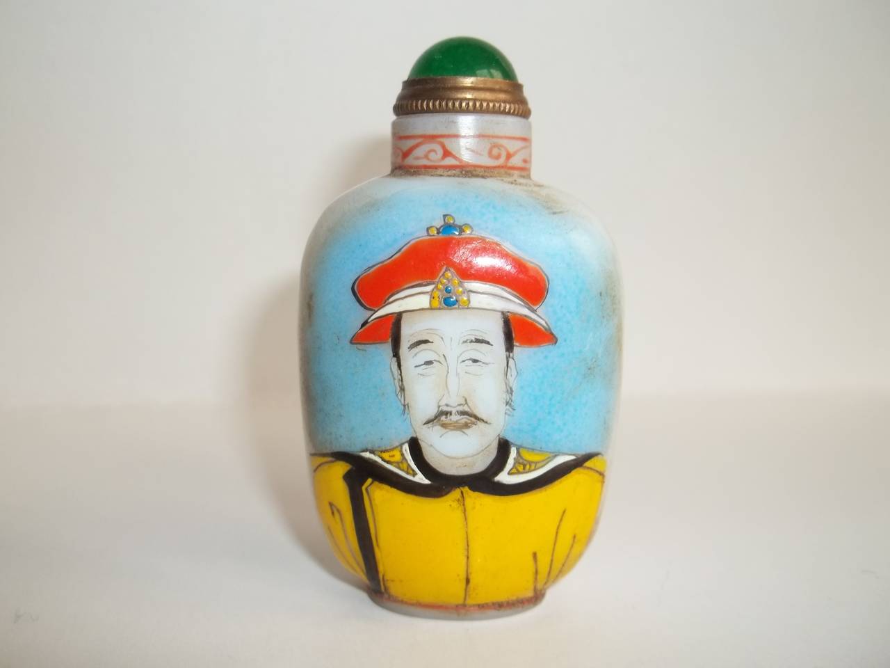 This is a very good 19th Century Chinese Snuff Bottle

It is made of white glass which has then been hand enamelled with the portrait of an Emperor on one side with Chinese characters on the reverse.

There is also a border pattern in red around