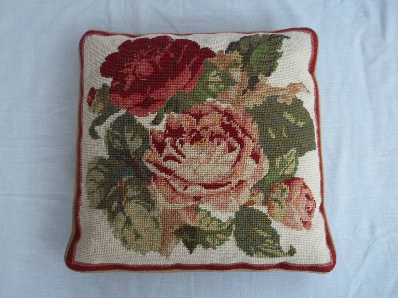 A good Needlepoint Cushion with a floral theme showing pink and red roses among green leaves on a light cream background.

It has a cream chenille backing with a zip to enable the stuffing to be removed.

There has been a small repair to the