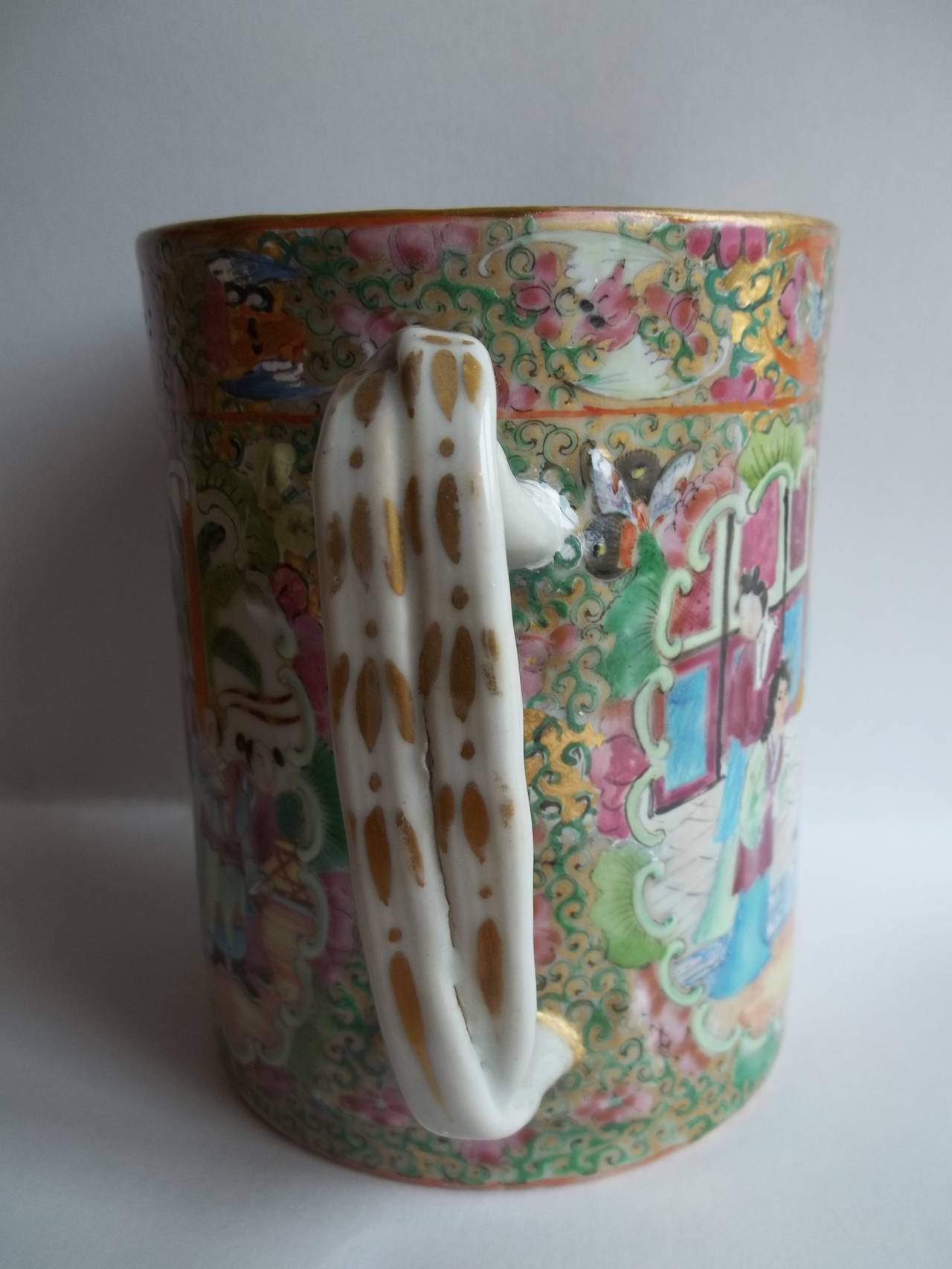 This is a very attractive piece of Chinese porcelain, dating to the 19th Century, pre 1850.

The mug has a cylindrical form with a nice twisted loop or branch handle. 

The decoration is typical rose medallion having three separate panels