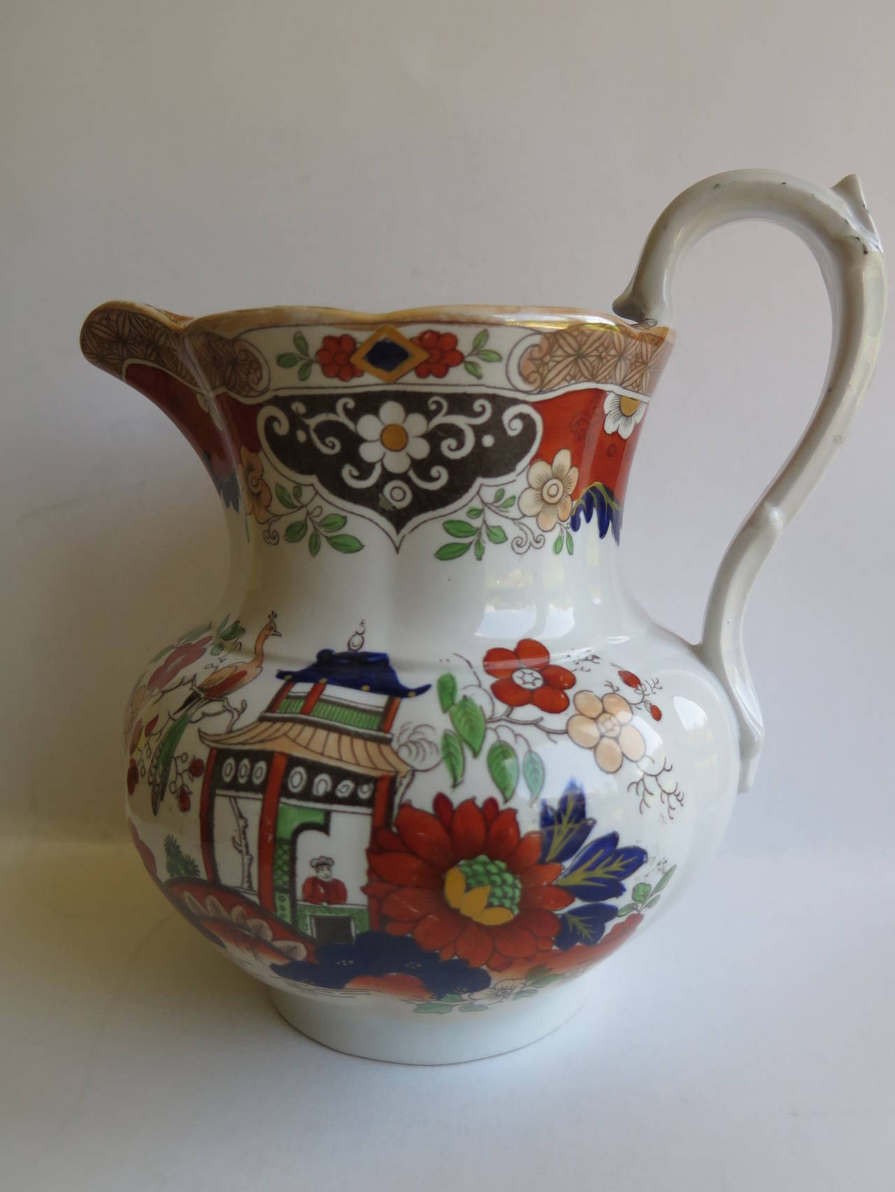 This is a good Ironstone pottery Jug or Pitcher with a high loop handle having an upper thumb rest. The jug has a moulded, vertically fluted shape with an integrated filter, formed into the inner top before the spout. 

The Jug has a typical