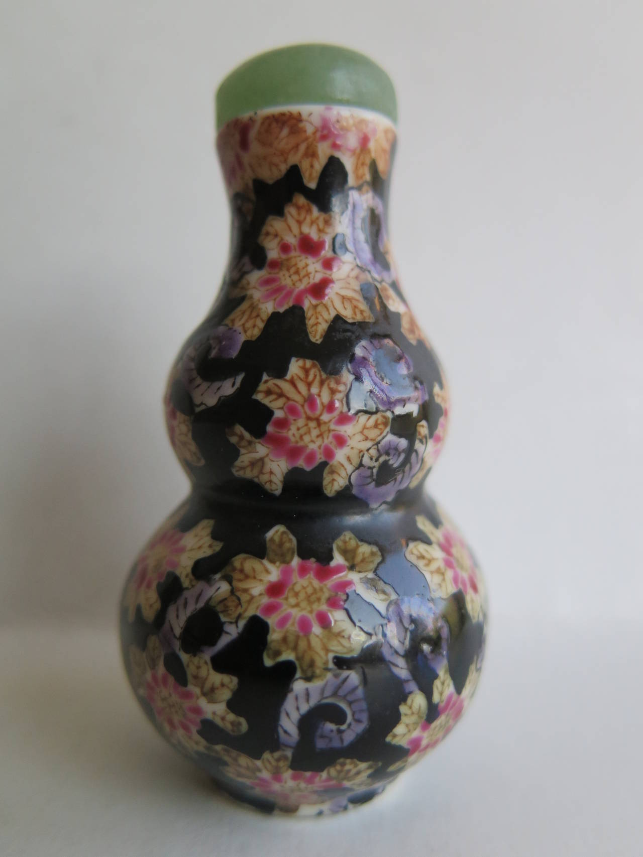 This is a beautiful Chinese porcelain snuff bottle which we date to the early 20th century.

The bottle is made of porcelain and has a classical double gourd shape.

It is decorated with an under-glaze floral pattern in a light beige color which