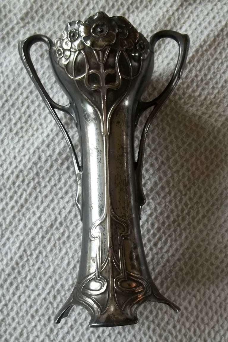 A beautiful silvered pewter twin handled  vase by the German manufacturer WMF.

This company pushed the curvi-linear style of Art-Nouveau metalwork to its limits producing lovely flowing designs.

This vase exemplifies this style, decorated in