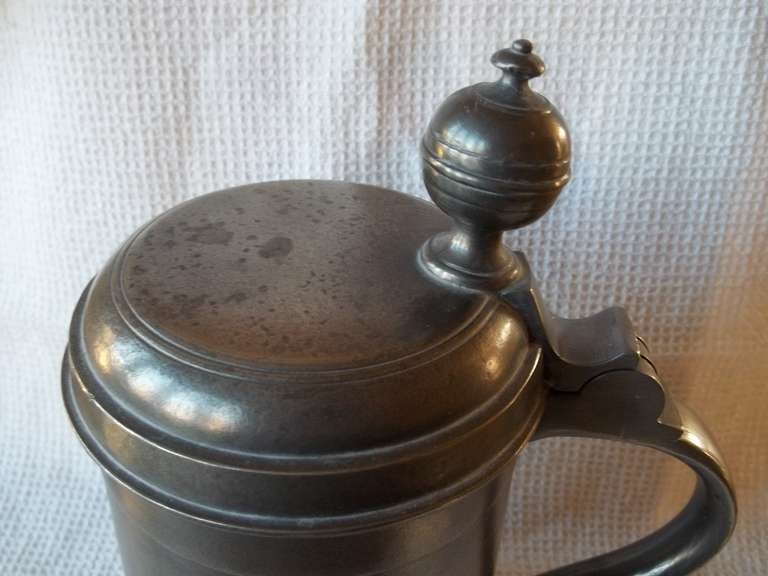 This is a superb PEWTER TANKARD of cylindrical slightly tapering body with a flaired base rim. It has a shaped C scroll loop handle with an upper thumb rest and a spherical finial to the lid section. This is a mid 18th century shape but I date the