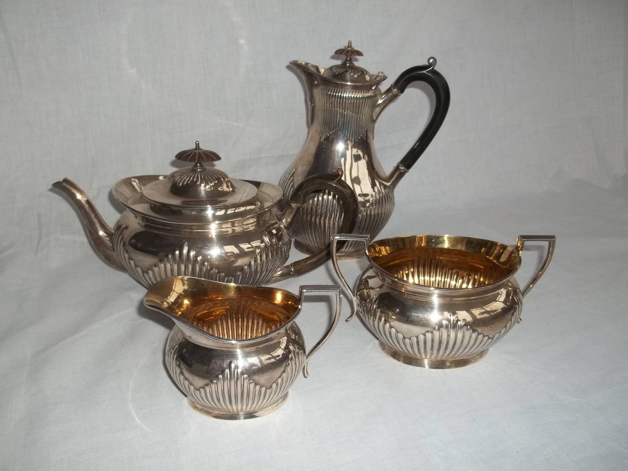 This is a heavy four piece, Solid sterling Silver, Tea and Coffee Service, made by Elkington & Co. Ltd in 1895.

There is a Tea-Pot, Coffee Pot, sugar basket and cream jug - all matching.
The sugar basket  and cream jug are gilded on the inside