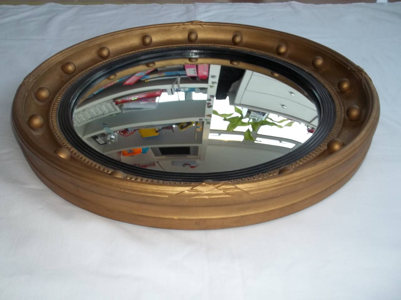 This is a good Circular Gilt Mirror in a popular Georgian Style. 

The frame is circular with a round gilt frame having good ball and ribbon detail.
The mirror has a circular hanging ring to the back

The CONVEX mirror glass is in good