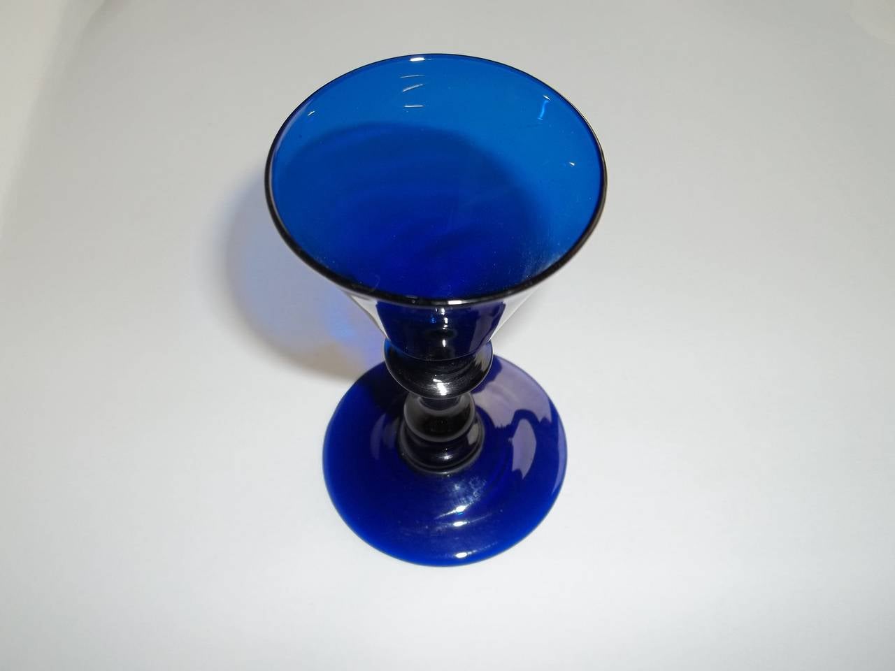 Early blue coloured Wine Glasses are rare.

The glass is free blown hand made blue lead glass.

This is a particularly nice example with a trumpet conical bowl having a bladed shoulder knop above a solid stem with a true baluster basal knop,