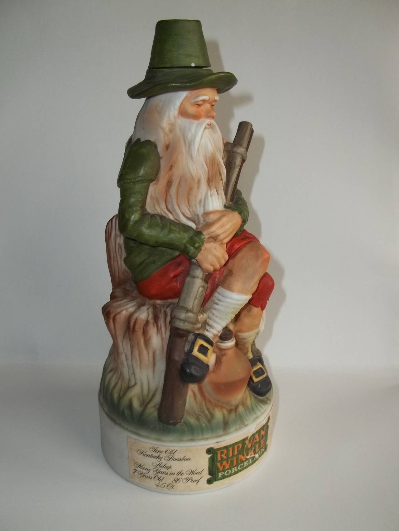 This is a good vintage collectible porcelain decanter for the very fine Rip Van Winkle Kentucky bourbon. Old Rip Van Winkle is hangin' with his gnomie, taking a snooze on the stump with gun in hand.

All original with corked top

The label is