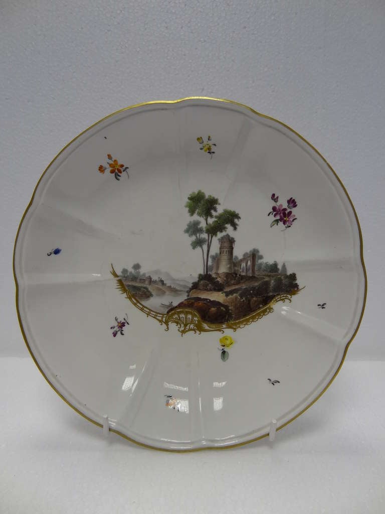 Porcelain Frankenthal Lobed Circular Saucer Dish. Central image of castle ruins,maybe a folly,by a river looking over to distant hills above a very finely executed gilt rococo scroll and with floral sprigs,gilding to rim. 

The Frankenthal