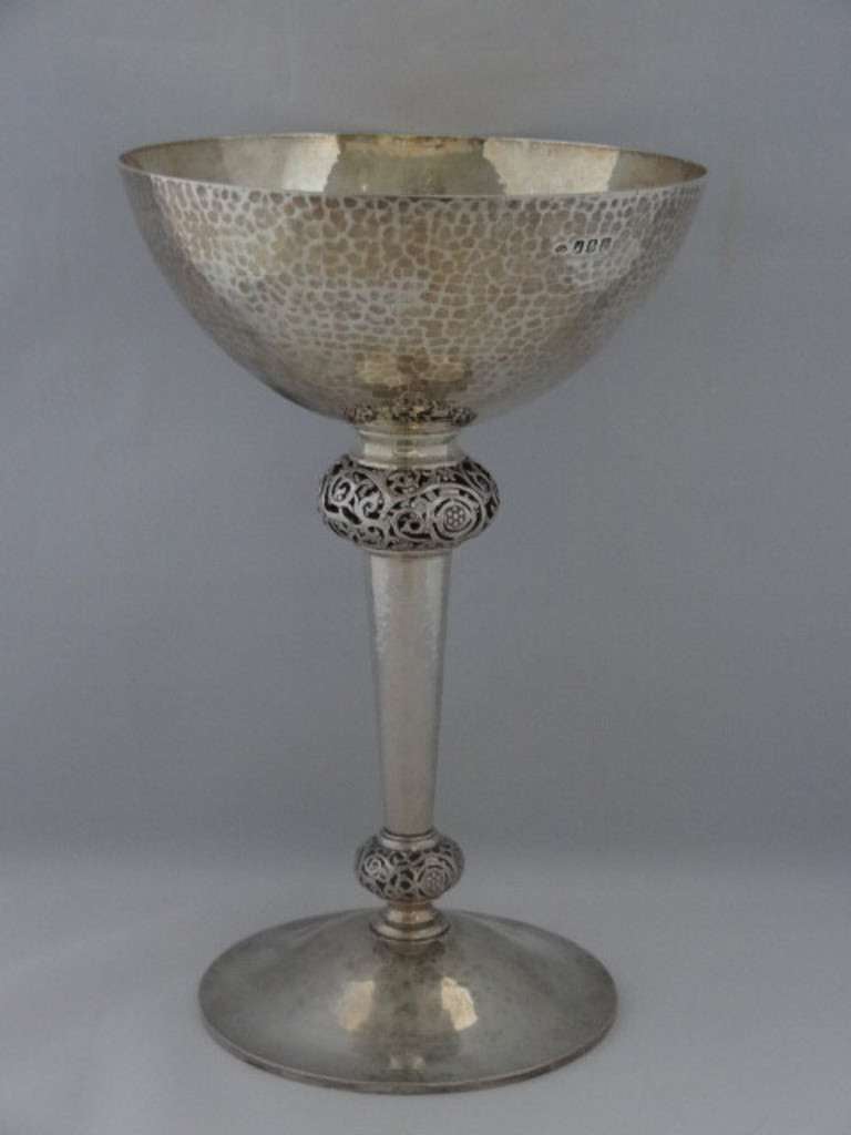 An Irish Arts & Crafts beaten silver goblet, by Wakeley & Wheeler, Dublin 1912. The simple bowl is set on a stem with two knops, each pierced with a Celtic design, rising from a circular foot. 

Signed/Inscribed/Dated: Clear WW mark of Wakeley &