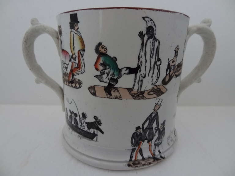Extremely unusual cylindrical waisted pearlware twin handed loving cup with printed transfers black and coloured enamels depict a woman kicking a man (her husband?), a child kicking a chained felon, the transfers in black to the lower section appear