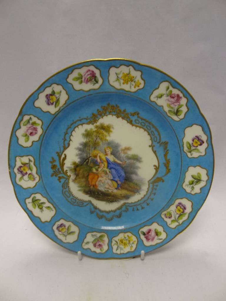 Porcelain ornamental Cabinet Plate with the blue interlaced mark encapsulating the date letters AA for 1778 and an unidentified ',' mark, a hard paste porcelain example. The ground is the bleu celeste. A central cartouche surmounted by gilding