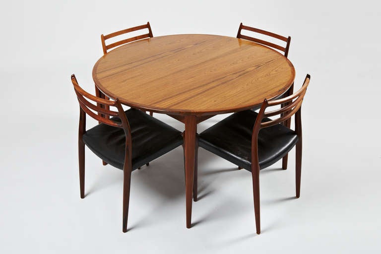 This listing is for a set of four rosewood dining chairs in original black leather and a rosewood dining table with one extensions leave.

The chairs are designed by Niels Otto Møller in 1962 and made/labeled by his workshop JL Møller between 1962