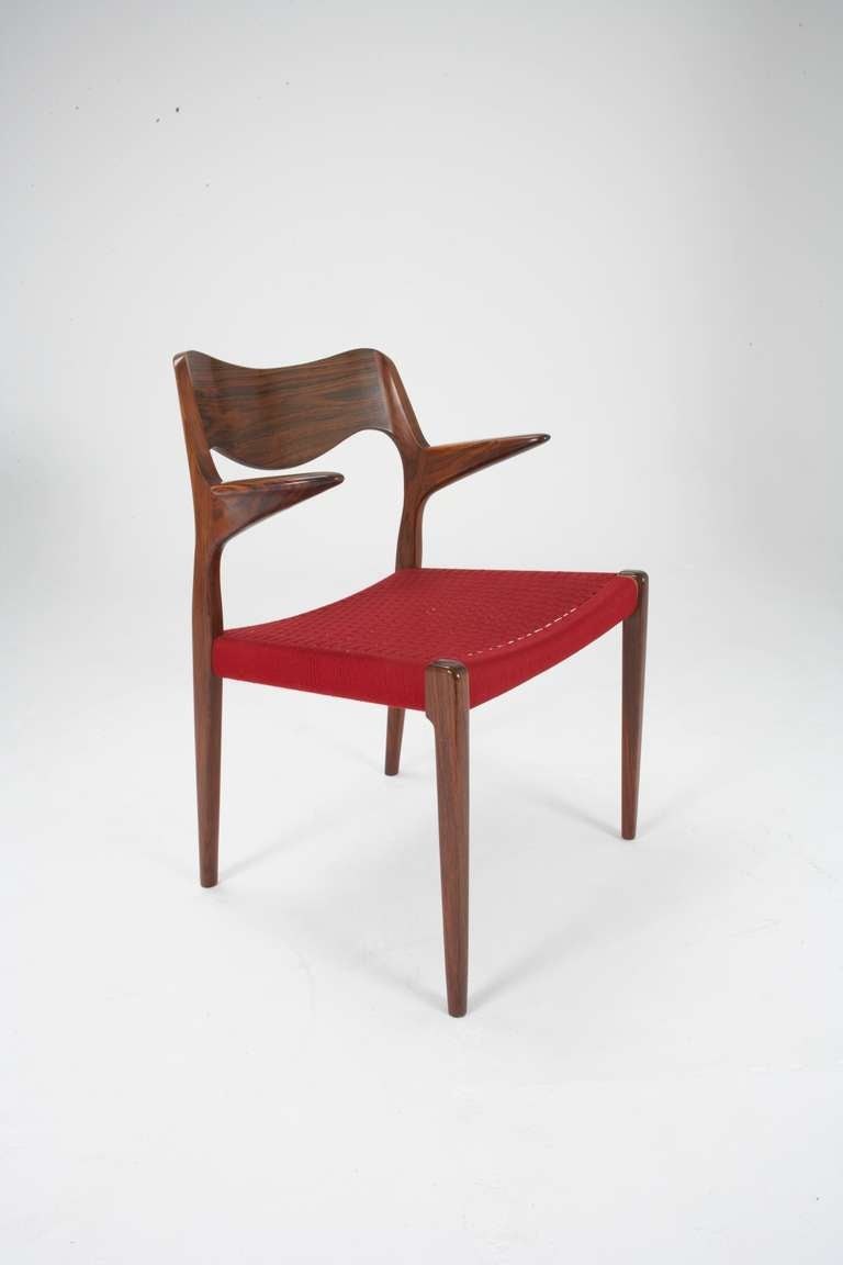 This listing is for a set of 12 rosewood dining chairs with arms in original red wool cord designed by Arne Hovmand Olsen in 1951 and made by JL Moller before 1969-70. To find such a large original set in perfect original condition is rare. The