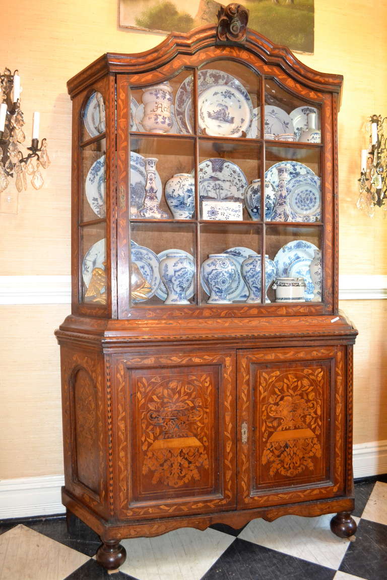 This beautiful Dutch Inlaid Breakfront with a shaped bonnet and skirt and distinctive moldings is perfect for displaying a collection of pottery as seen in this picture.  The top of the piece has a door and side panels with glass panes over two