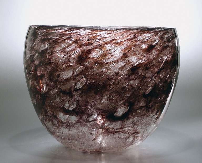 Mould blown tall bowl made of thick colourless glass with veils of air bubbles and shot through with deep reddish purple tints. The color and air bubbles result into a spectacle of colourful ever changing ‘dancing’ light effects when the bowl is