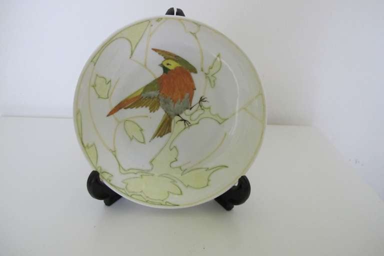 This Art Nouveau eggshell porcelain saucer by Rozenburg has a hand painted stylised decoration of a bird in the midst of branches and leaves.

The Rozenburg Royal Delftware Factory (1883-1917) produced internationally renowned pottery. The