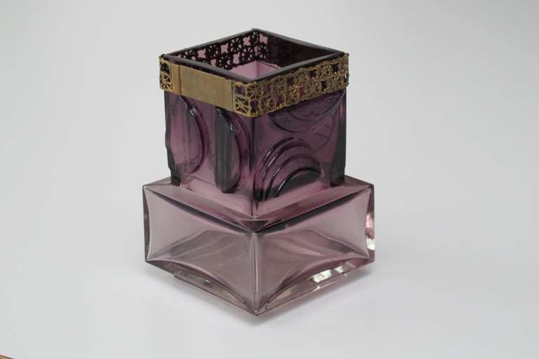 Purple art glass vase with circular shapes on all sides of the vase and a patterned metal band, designed by Pentti Sarpaneva. The glass was manufactured at Oy Kumela and the matching bronze cylinder at Turun Hopea of Finland.

Pentti Sarpaneva,