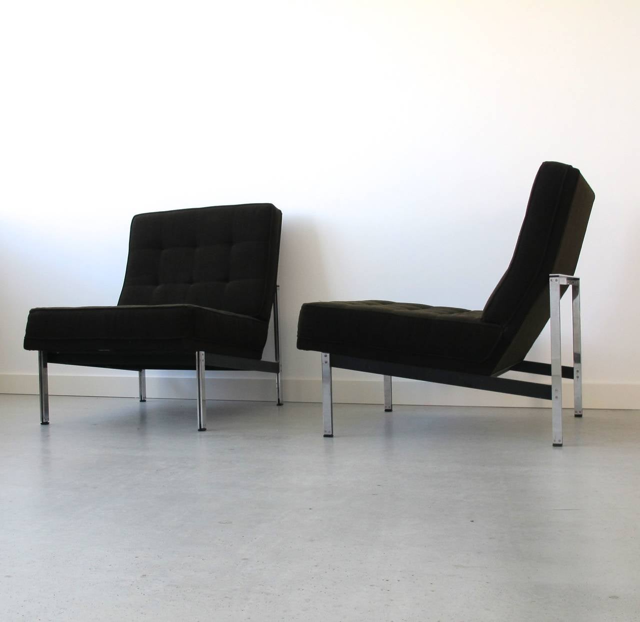 Pair of parallel bar lounge chairs designed by Florence Knoll and executed by Knoll International, circa 1955. Capitonated dark brown original upholstery; partly chromed, partly black lacquered metal base.

This set of timeless chairs is in a