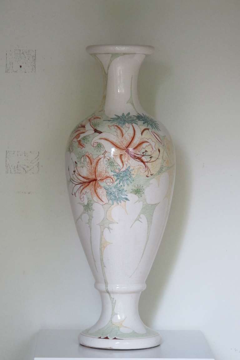 This very large Art Nouveau vase, circa 1905. It was produced by the Gouda Royal Faience factory South-Holland, as can be seen by the marks on the bottom. This vase has a beautiful hand-painted floral decor with lilies among other things.