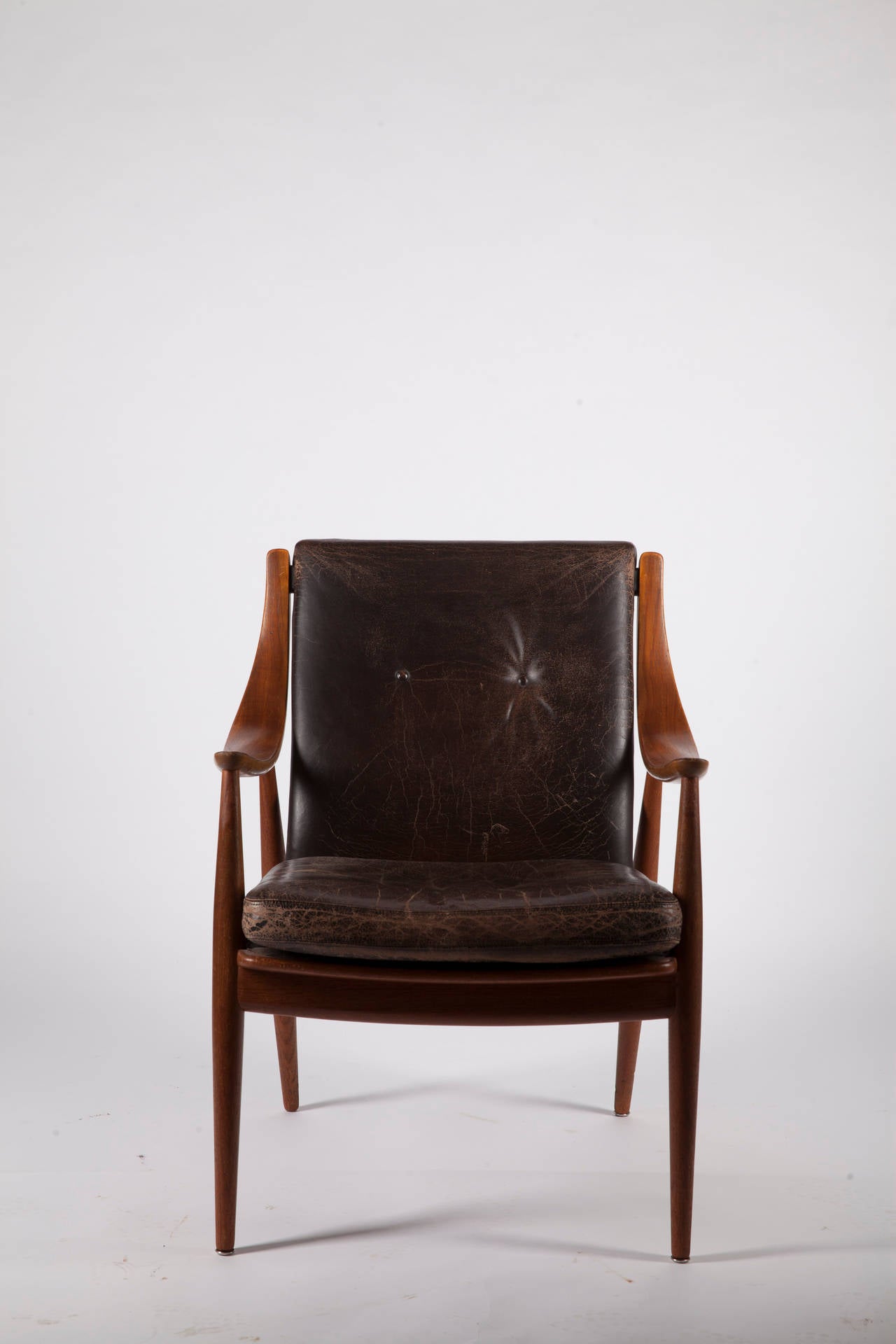 A characteristic easy chair with original leather upholstery and bend armrests from 1953. 
The chair, known as model 148, was designed by Peter Hvidt (1916-1986) and Orla Mølgaard-Nielsen (1907-1993) and produced by the Danish company France &