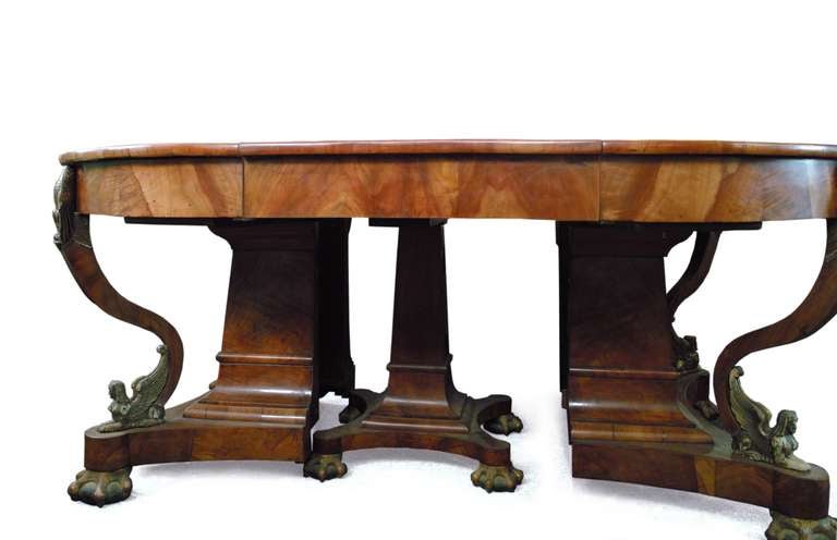 A German extension table resting on eight claw-feet showing gilt sphinxes and Prussian eagles. The pedestal base dividing into two halves to reveal a center post. Designed under the influence of Karl Friedrich Schinkel and Friedrich Gilly this
