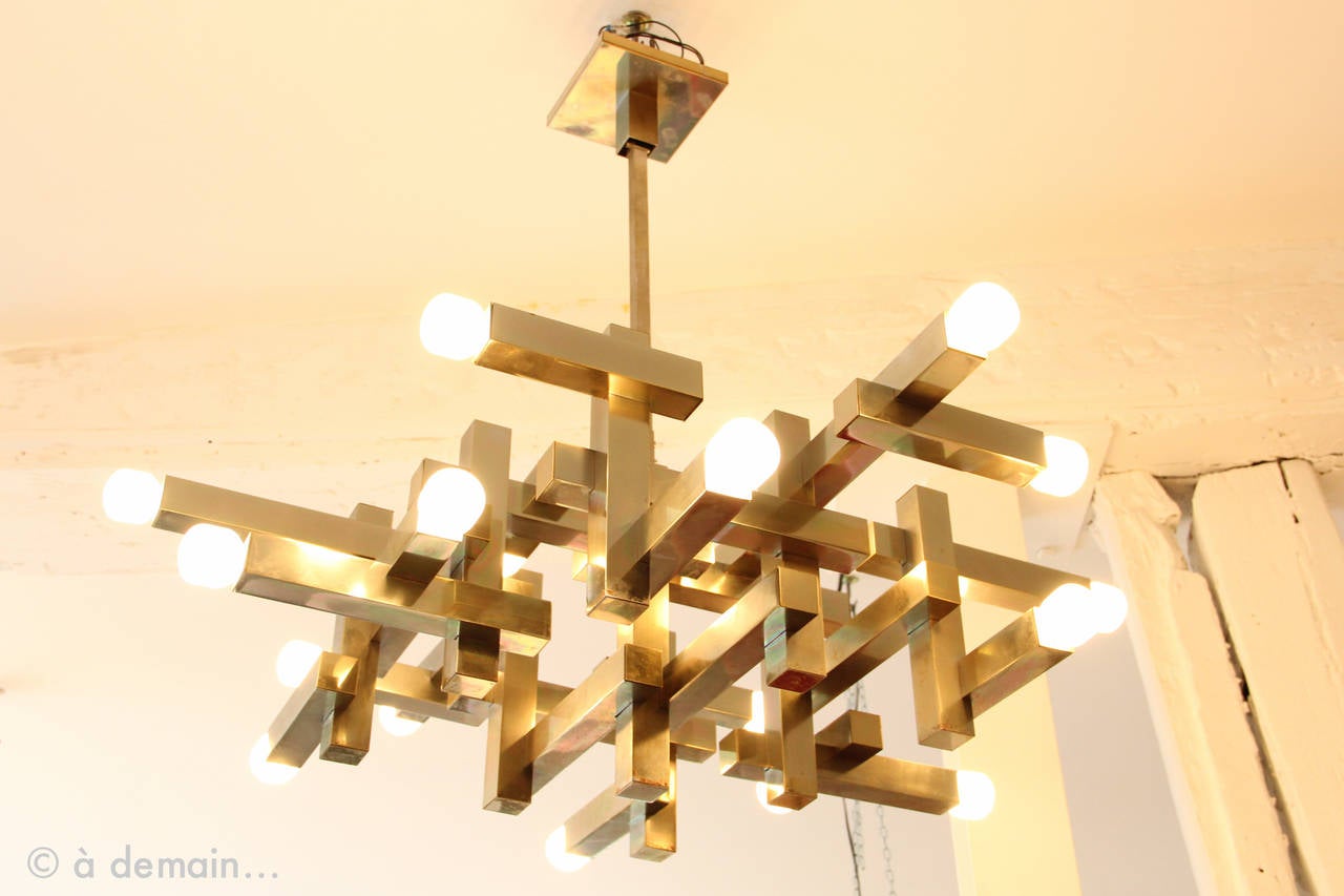 1970s Gaetano Sciolari Ceiling Lamp called Eighteen Light because it presents 18 lamps. Beautiful cubic steel structure made of square tubes. 
Sciolari style is famous for being edgy and futuristic, with great optical effect and a pretty warm