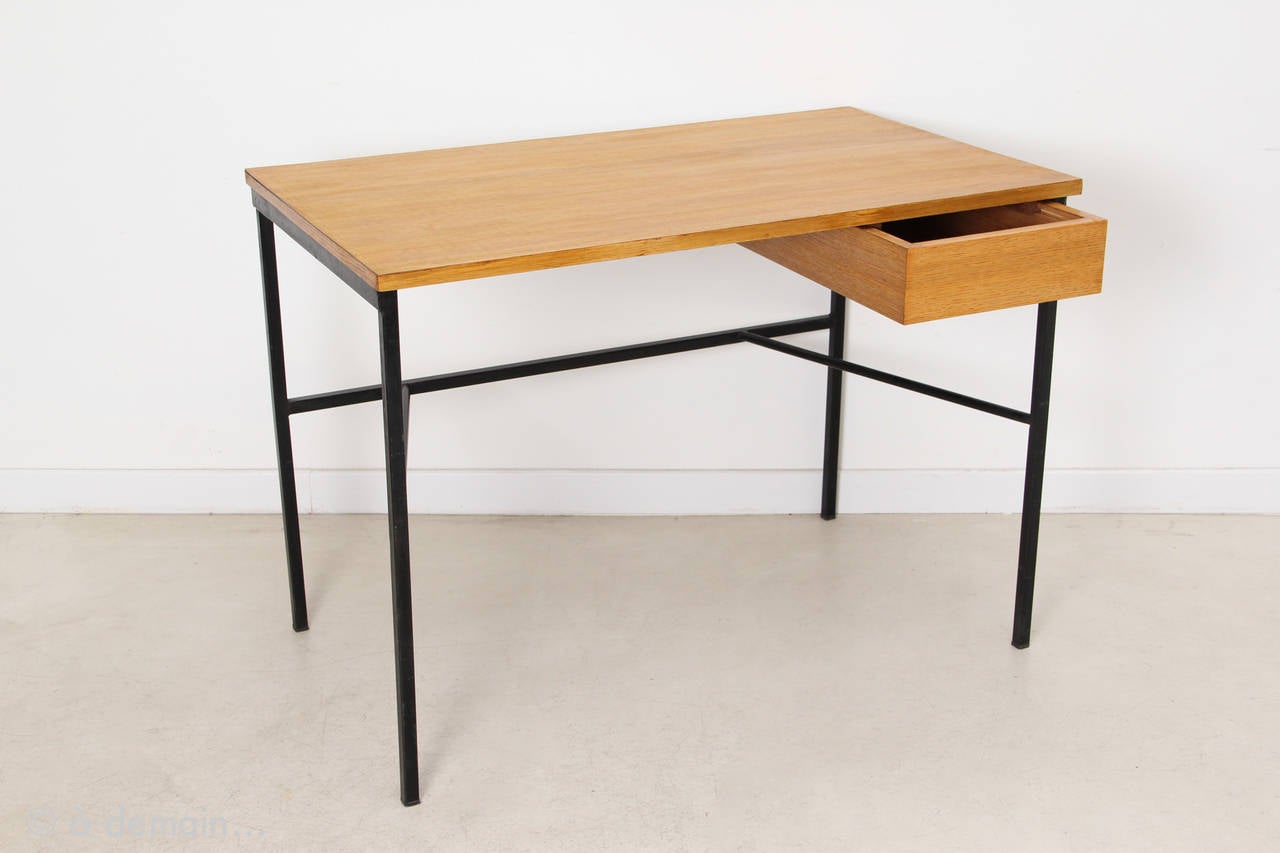 Made of wood and black lacquered metal structure, the CM174 desk is a rare and instantly recognizable masterpiece of the French designer Pierre Paulin. With its small drawer, its charm is not flashiness because it is discreetly elegant and