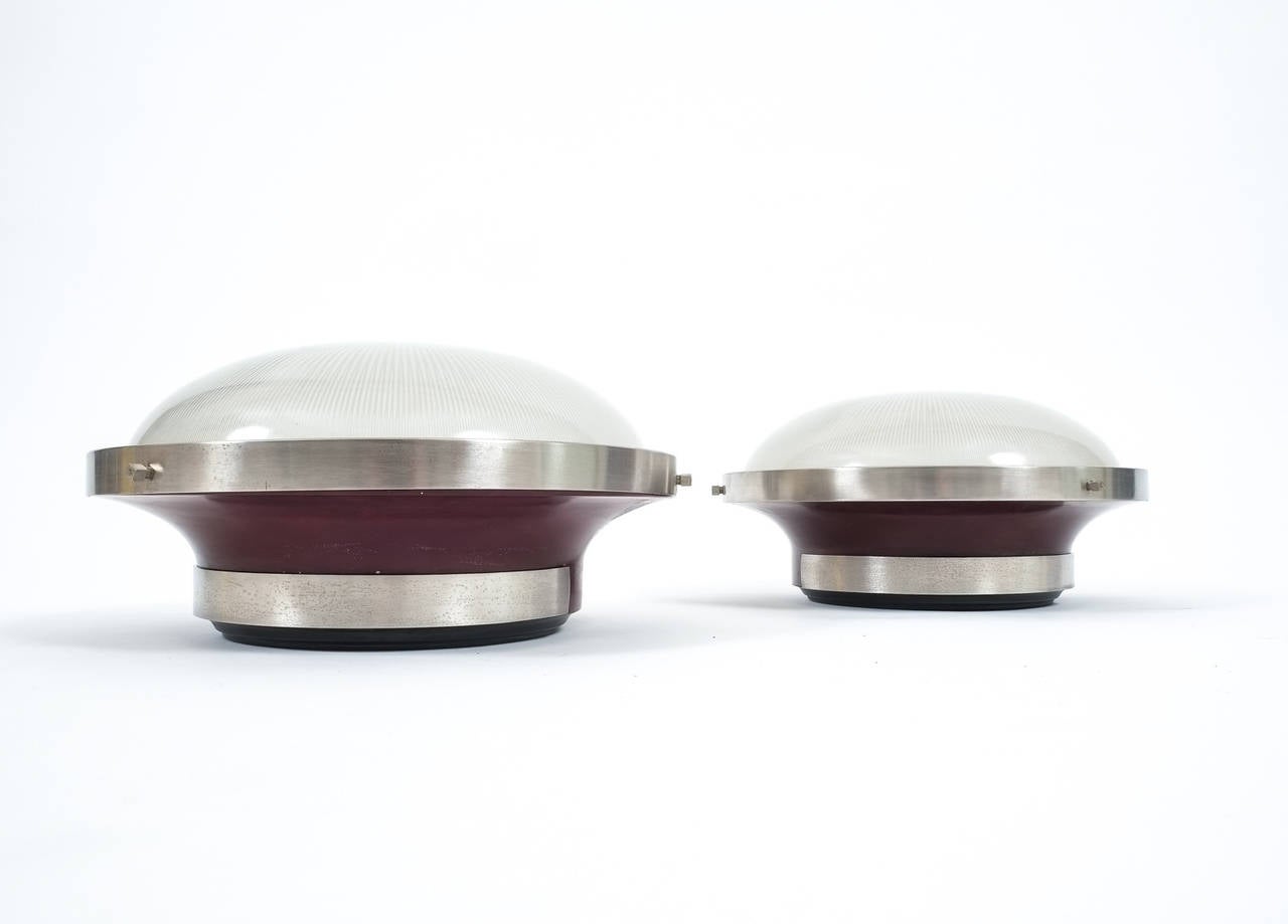 Very elegant fixture designed by Sergio Mazza for Artemide.

Enameled metal base in dark red with metal accents and glass dome. The light might either be used as sconces of flush mounts. 