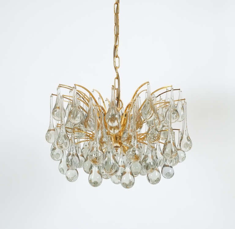 Beautiful multi-tiered tear drop chandelier composed of a multitude of handblown smooth Murano glass drops hanging from a delicate gilt brass hardware. It's in excellent condition with a total of eight-light bulbs. Newly rewired. Overall height is