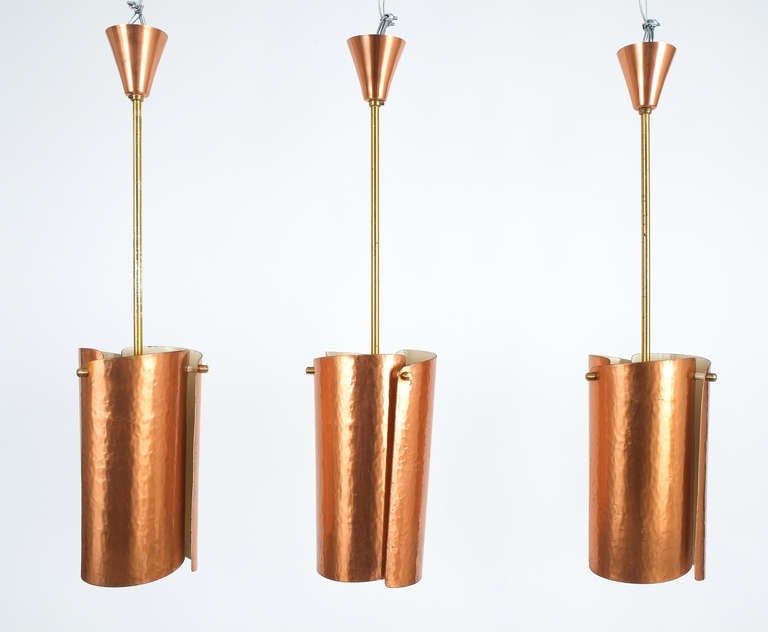 Beautiful set of three copper pendant lights from Italy with curved and hammered copper sheets. One bulb each with 60W max. The brass rods may be shortened or customized or replaced at will.
Priced and sold individually.