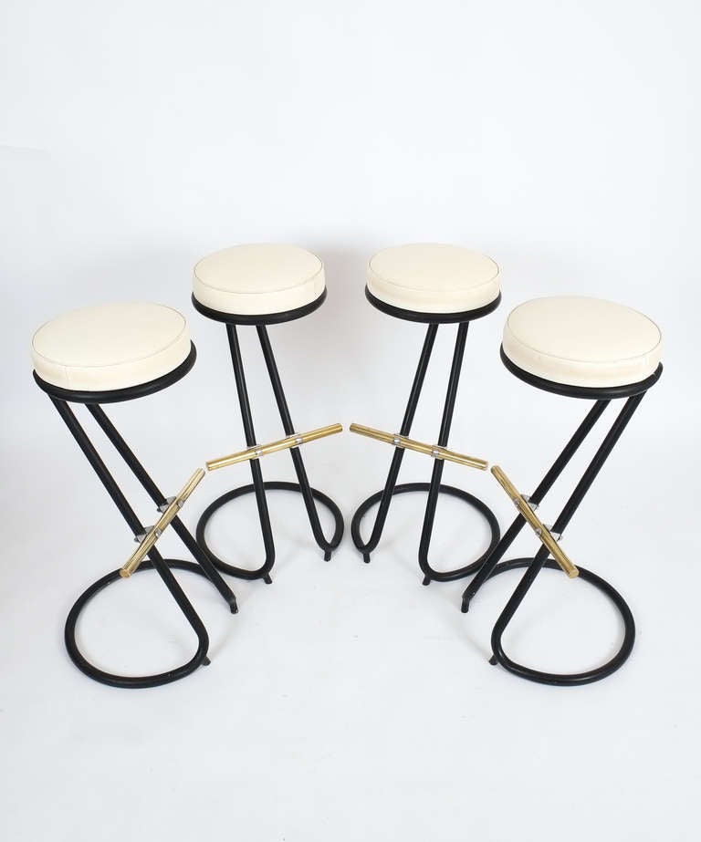 Beautiful Gastone Rinaldi barstools consisting of a black steel frame, brass footrest and white faux leather seats. 
Condition is excellent. Four pieces are available, sold individually.