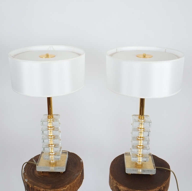 Beautiful pair of large table lamps by Bakalowits & Sohne Austria. The table lights are composed of smooth and heavy stacked cast glass blocks and gold plated brass hardware. 
The lights are in excellent as new condition and equipped with new