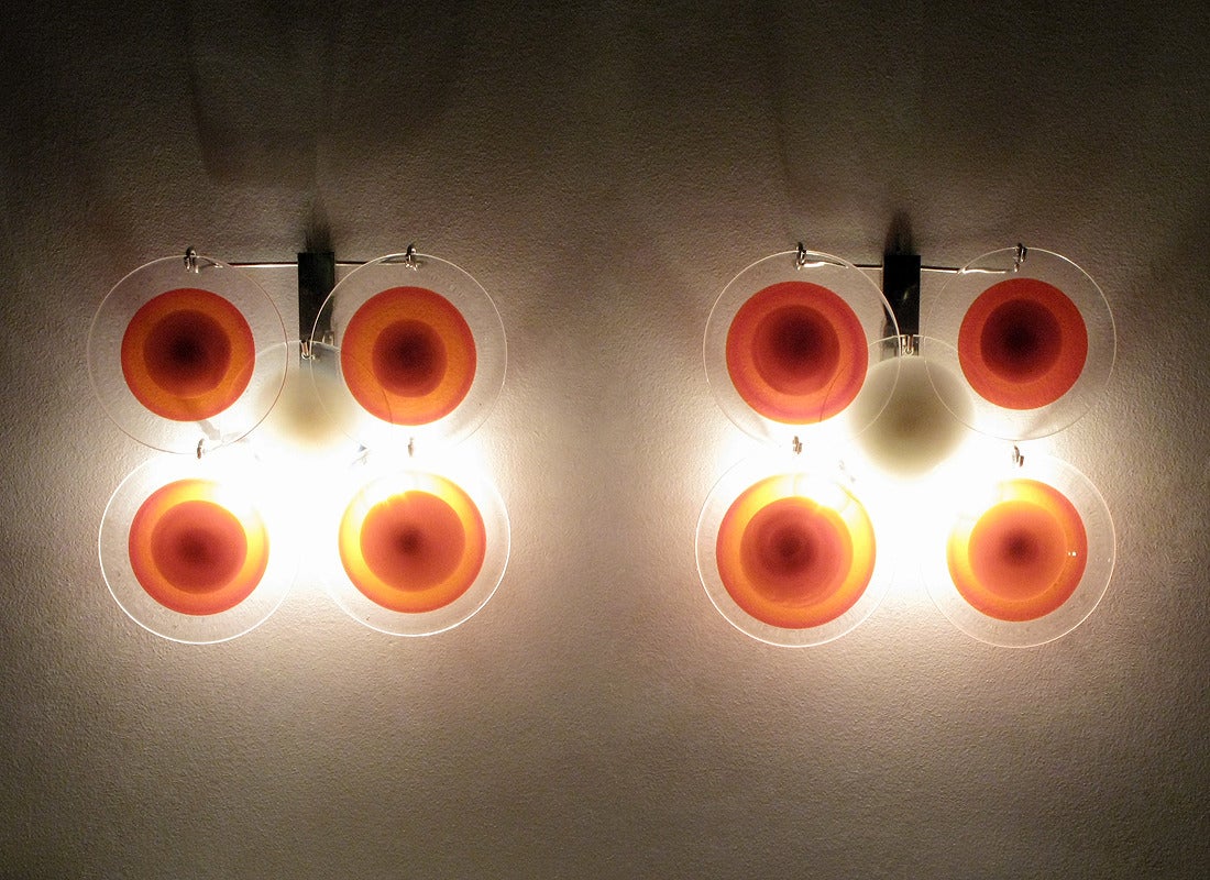 A pair of striking 1970s sconces by Italian makers Vistosi.

Each sconce is comprised of five large glass disks, the central with white center, the outer four with red and orange centers. They cast a warm, diffused light.

Each disk is