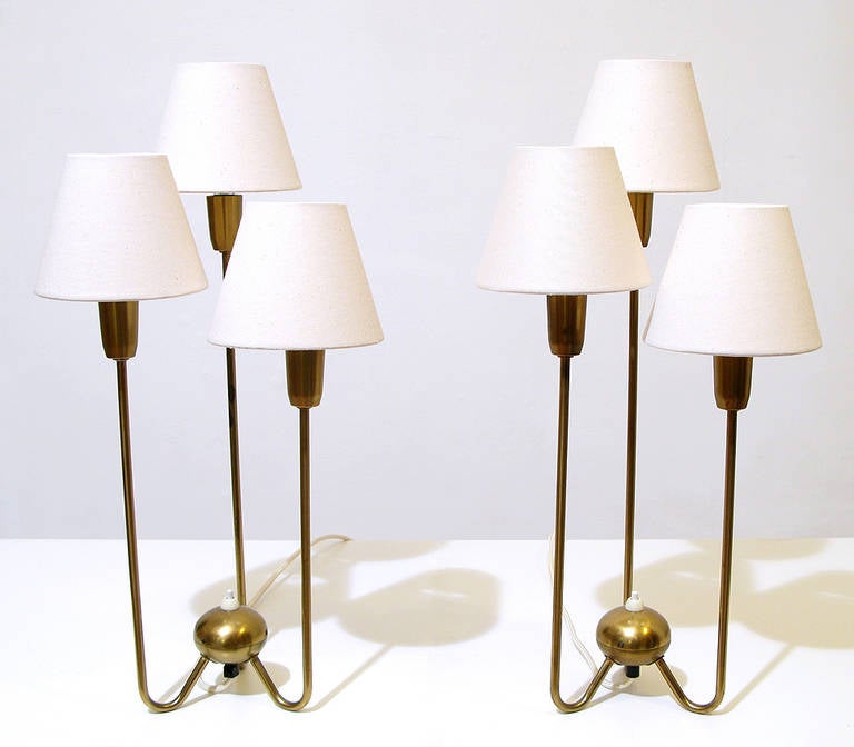 A pair of original 1950s three-arm table lamps by Swedish makers Asea. With cream lamp shades and braided cream cords, these brass lamps are in excellent restored condition. The Asea manufacturer marks are stamped to the undersides. They would