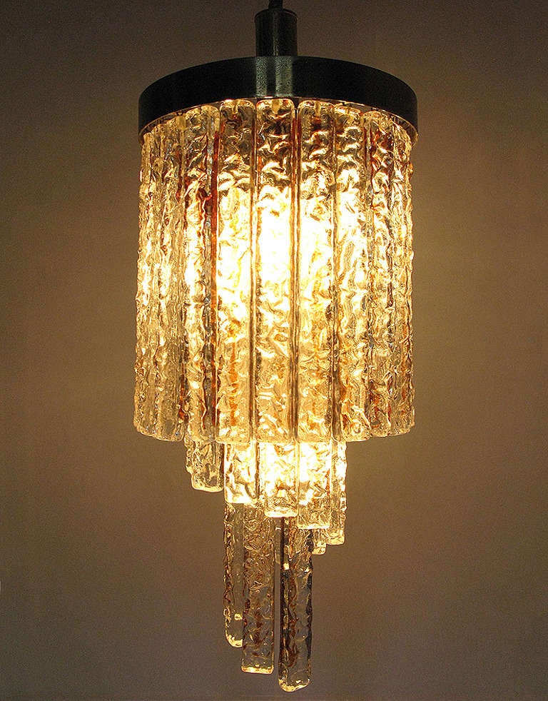 Drop: 110cm
Height: 55cm
Diameter: 27cm

A 1950s spiral chandelier in thick Murano glass and brass by Italian makers Mazzega.

Comprised of forty thick clear glass pieces, an amber strip at the center of each, it casts a soft, warm light. Each