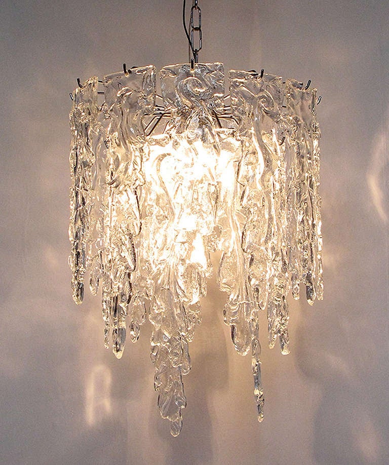 Measures: Drop 100cm
Height 58cm
Diameter 44cm

A large, 1960s art glass chandelier by renowned Murano makers Mazzega.

It is comprised of 24 heavy art glass shards in three circular tiers. There are twelve pieces on the outer tier, nine in