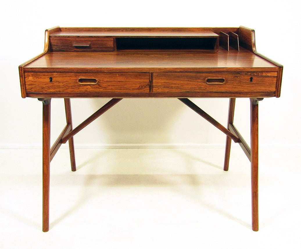 A striking 1960s rosewood desk by Arne Wahl Iversen for Vinde Mobelfabrik.

This chic desk features three drawers, large writing surface and a three-slot letter rack.

The angled legs and sculpted form make this desk visually appealing from all