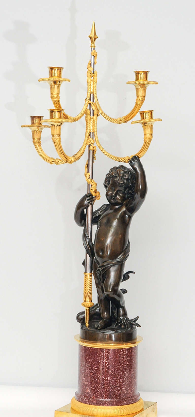 both with patinated bronze putti holding the stem aloft, on an annular porphyry base with ormolu plinth.