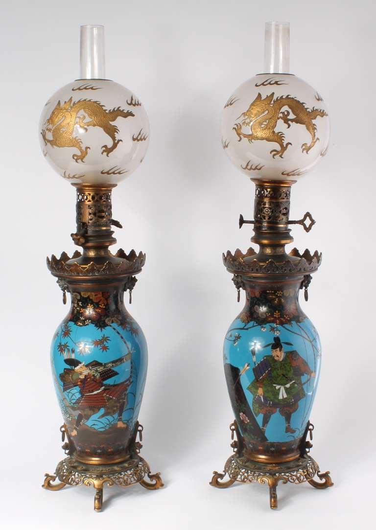 A pair of fine oriental style cloisonné oil lamps, Barbedienne circa 1880

Both with a Japanese warrior among foliage, pierced bronze ornament signed 'Barbedienne' for the Bronzier on the base, glass ball decorated with a gilt dragon.