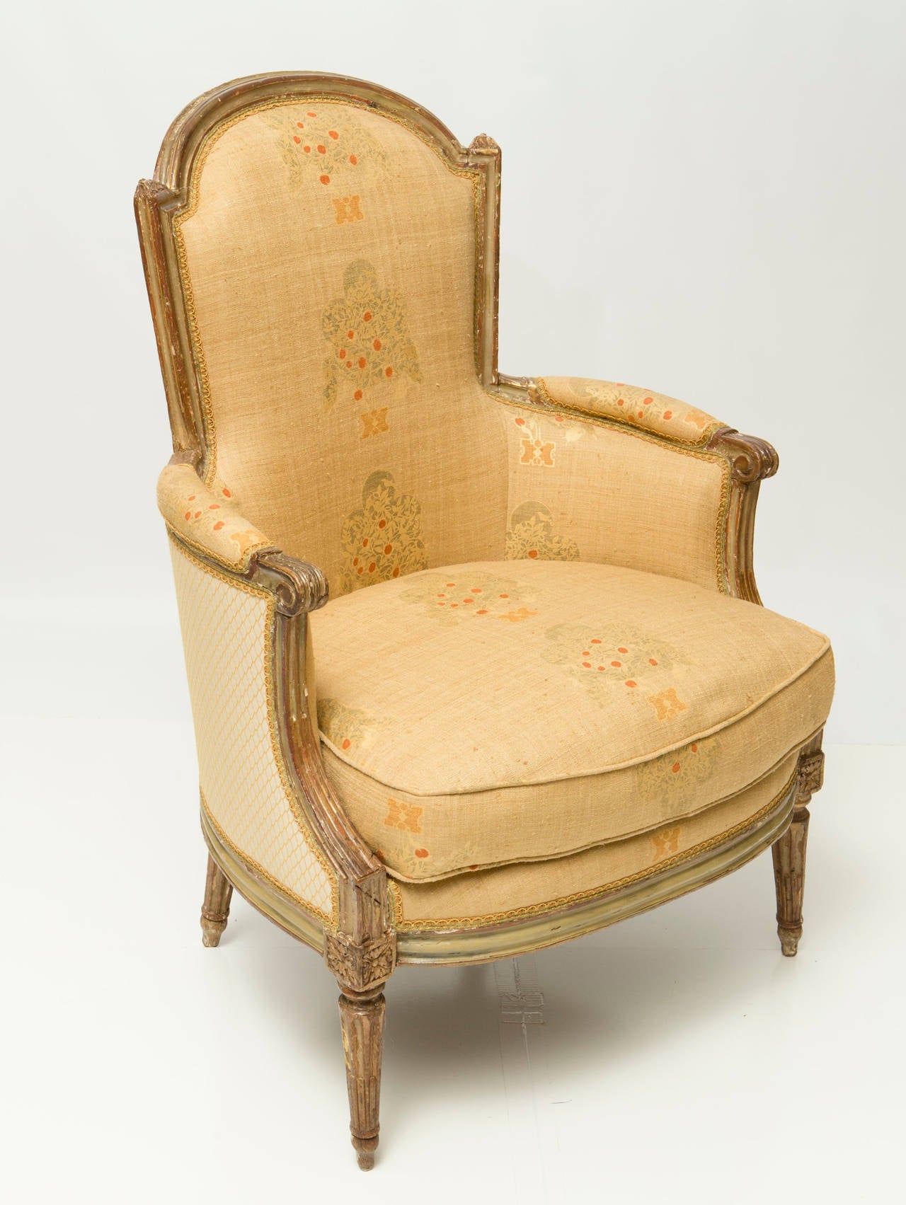Decorative French Bergere Chair with yellow floral upholstery and painted carved wood legs. Contrasting fabric on the back and sides.