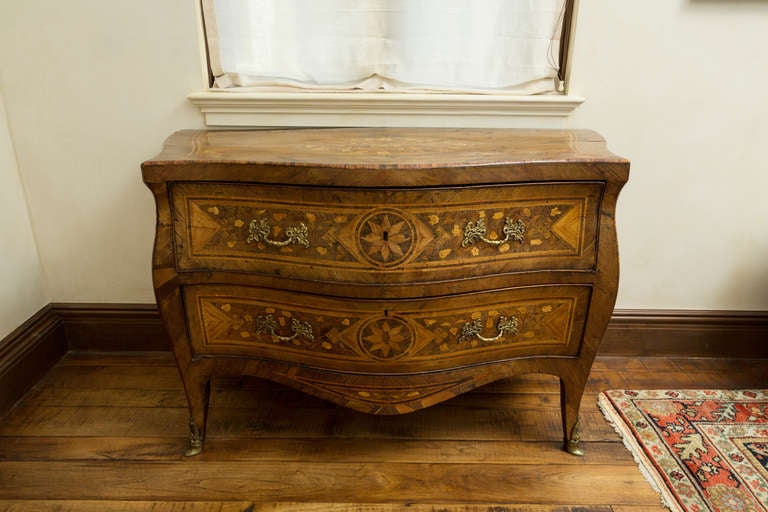 18th century Italian walnut veneered commode probably Naples, of serpentine and bombe shape, profusely inlaid with Dutch floral marquetry and star bursts with fine cast gilt bronze handles and feet capped with gilt bronze sabots, circa 1750.
