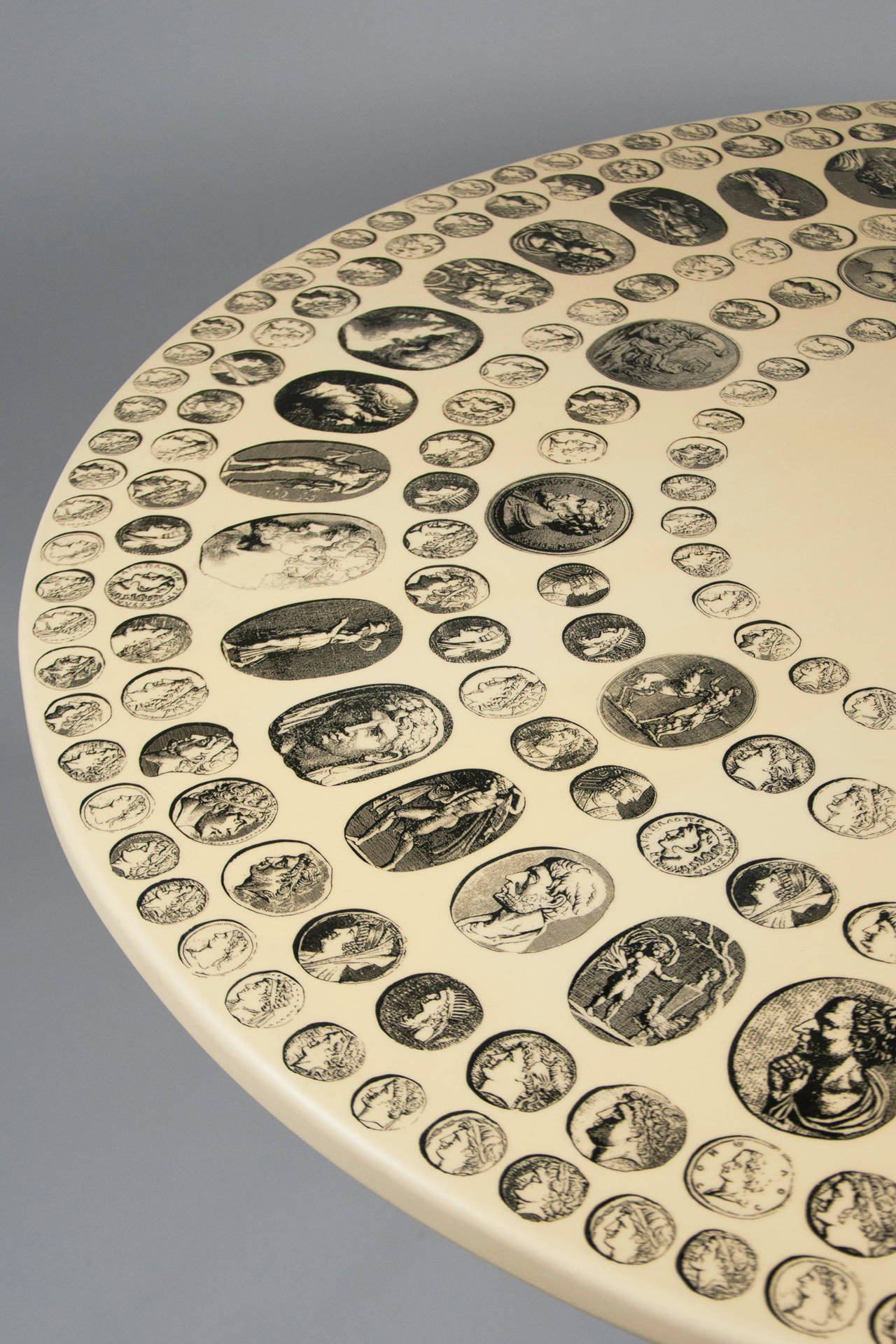 Laminated top with hand-colored lithograph on wood depicting collection of dozens of Classical Roman cameos, Fornasetti model Cammei, raised on enameled steel and brass four-legged base.

 