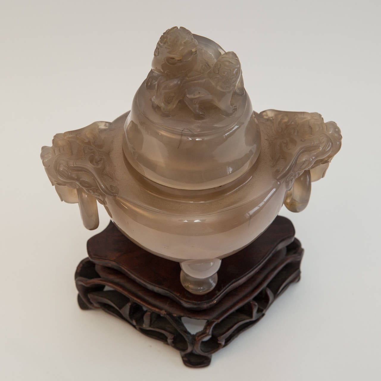 A very fine tripod censer, high relief carved from a translucid agate stone. The sides of the rim flanked with two large lion-mask loose-ring handles and the dome cover with a two lions finial. Finely carved dismountable stand. Partly remaining