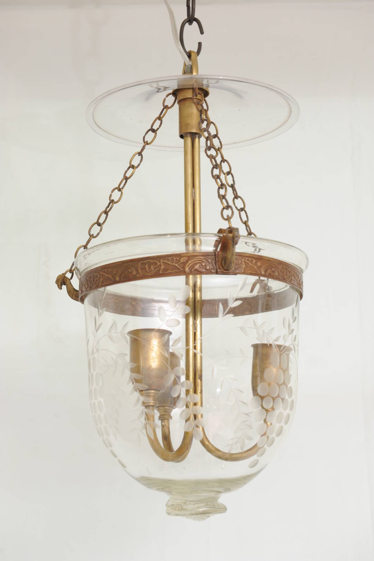 Pair of hand-blown, early 20th C. bell jar hall lanterns.  This pair has classic grape vine etching, glass pontil, original brass hardware, smoke cap and electrified for modern use with three candelabra bulbs.  Elegant and classic lighting.  English.