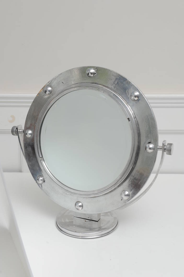 This is an original ship's chrome/aluminum ship's window converted to an adjustable vanity mirror. Frame and concept designed by Deborah Lockhart Phillips. New rivets were put back in to complete the look (the old ones are lost when the windows are