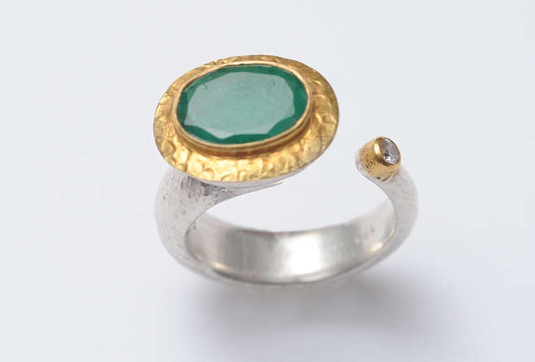 An unusual asymmetrical ring constructed of hammered sterling and a weighted 22K Gold (not a vermeil) with a large, faceted emerald and small diamond on the side.  Ring size is 6 3/4.