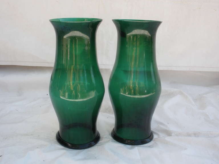 Pair of magnificent size hand-blown hurricane shades (or shields) in an emerald green color with a rolled rim at the bottom.