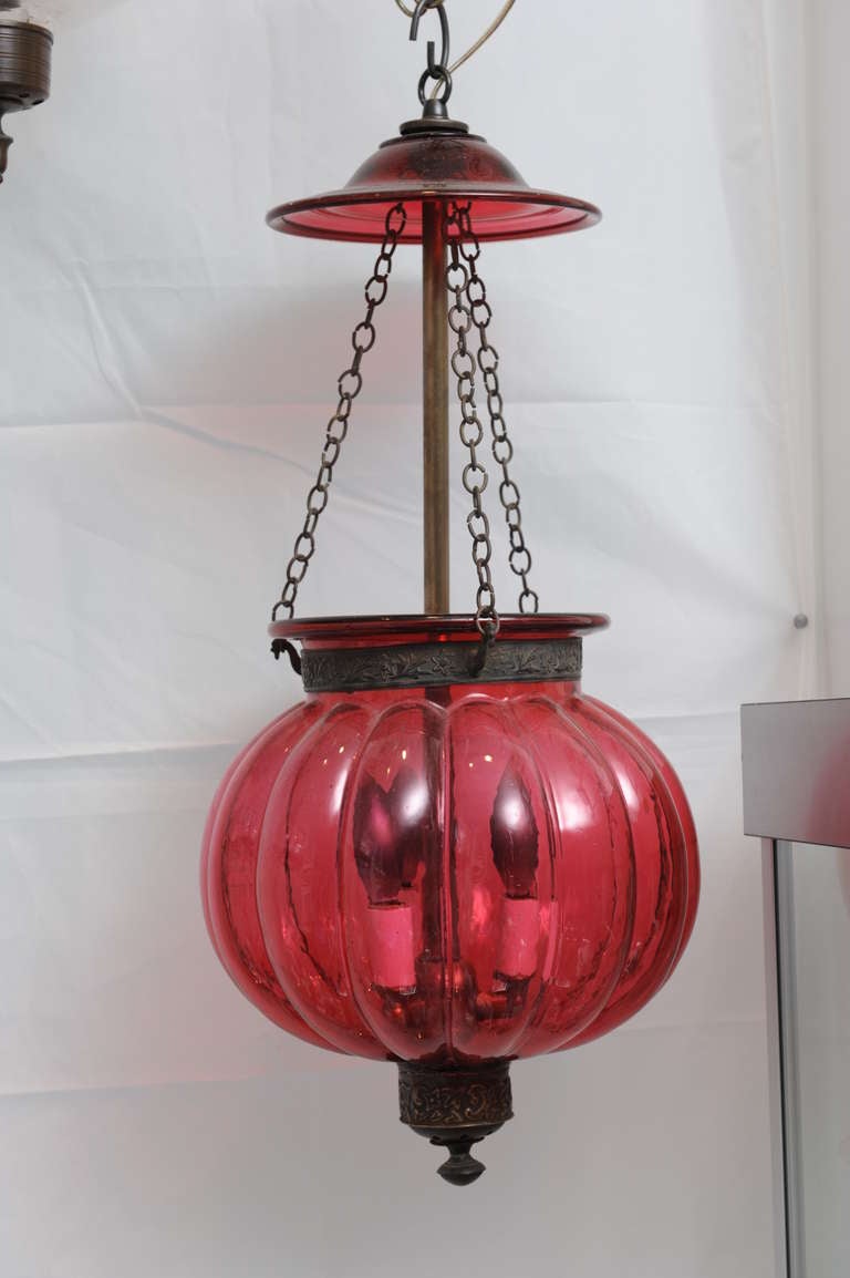 Late 19th century handblown cranberry hall lantern in a melon shape with embossed brass finial and band, and original smoke cap. Electrified for modern use and takes three candelabra bulbs.