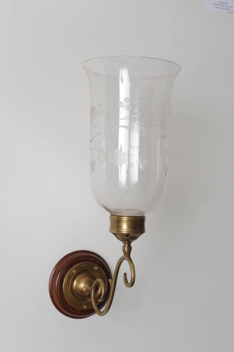 This is a pair of late 19th century handblown hurricane shades with vine etching and tulip shape on brass sconce arms and mahogany back plate. English. These can be electrified with a candle sleeve and a candelabra bulb for $85. Arms are not as old