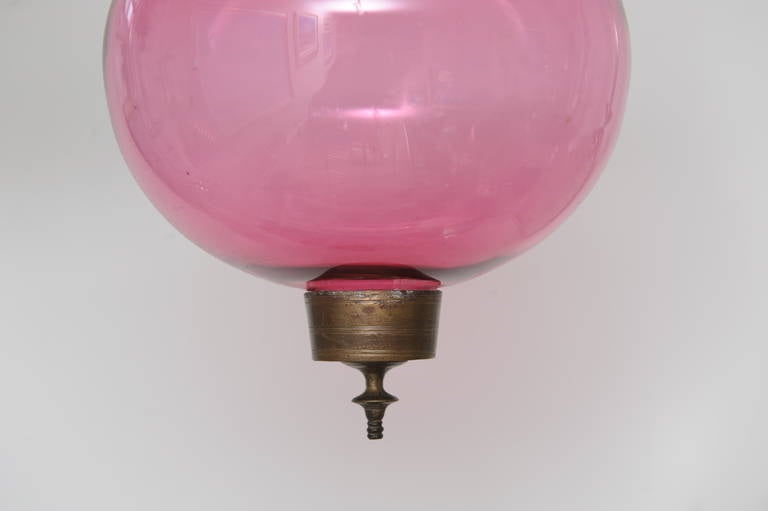 Lovely, 19th century handblown cranberry globe hall lantern complete with smoke cap. Brass chain, candle holder and embossed brass band with griffins holding the chain. English. Excellent condition. Not electrified, but could be.